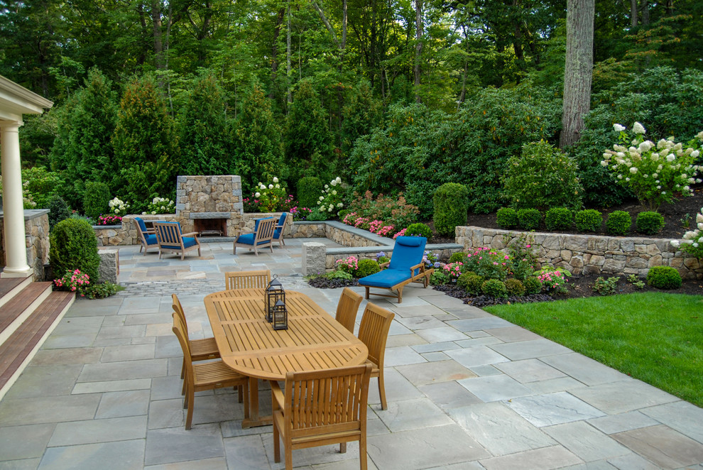 Immagine di un patio o portico classico di medie dimensioni e dietro casa con un focolare e pavimentazioni in pietra naturale