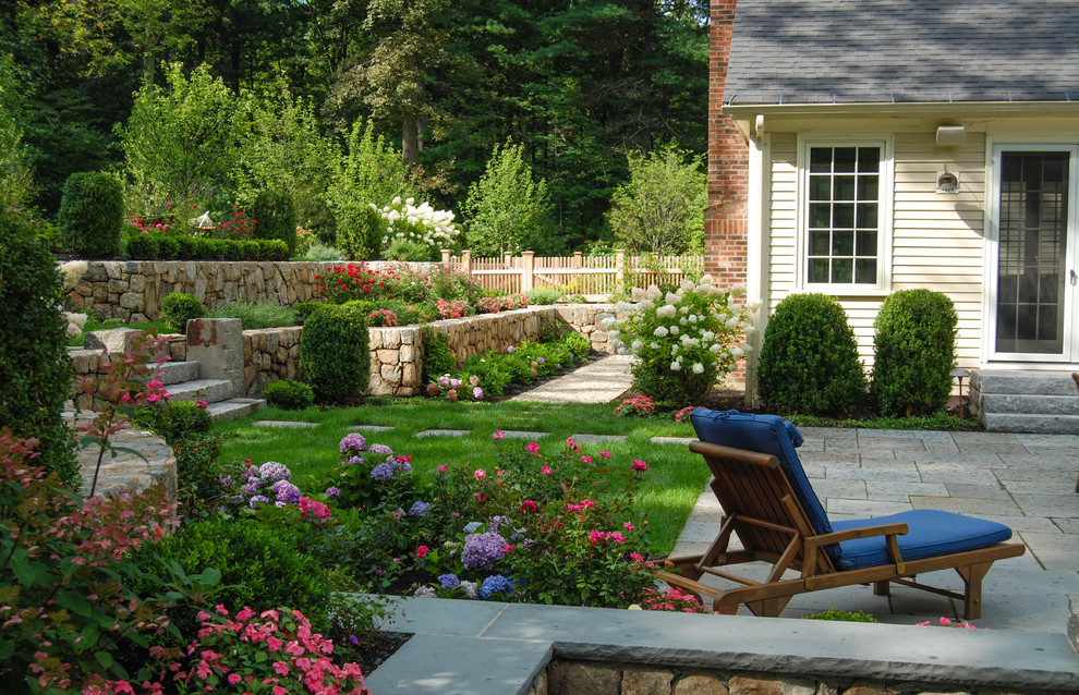 Idée de décoration pour un jardin arrière tradition de taille moyenne avec des pavés en pierre naturelle.