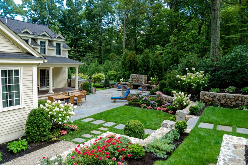 Imagen de jardín clásico de tamaño medio en patio trasero con muro de contención, exposición total al sol y adoquines de piedra natural