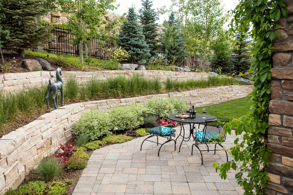 This is an example of a large traditional side formal partial sun garden for summer in Denver with a retaining wall and concrete paving.