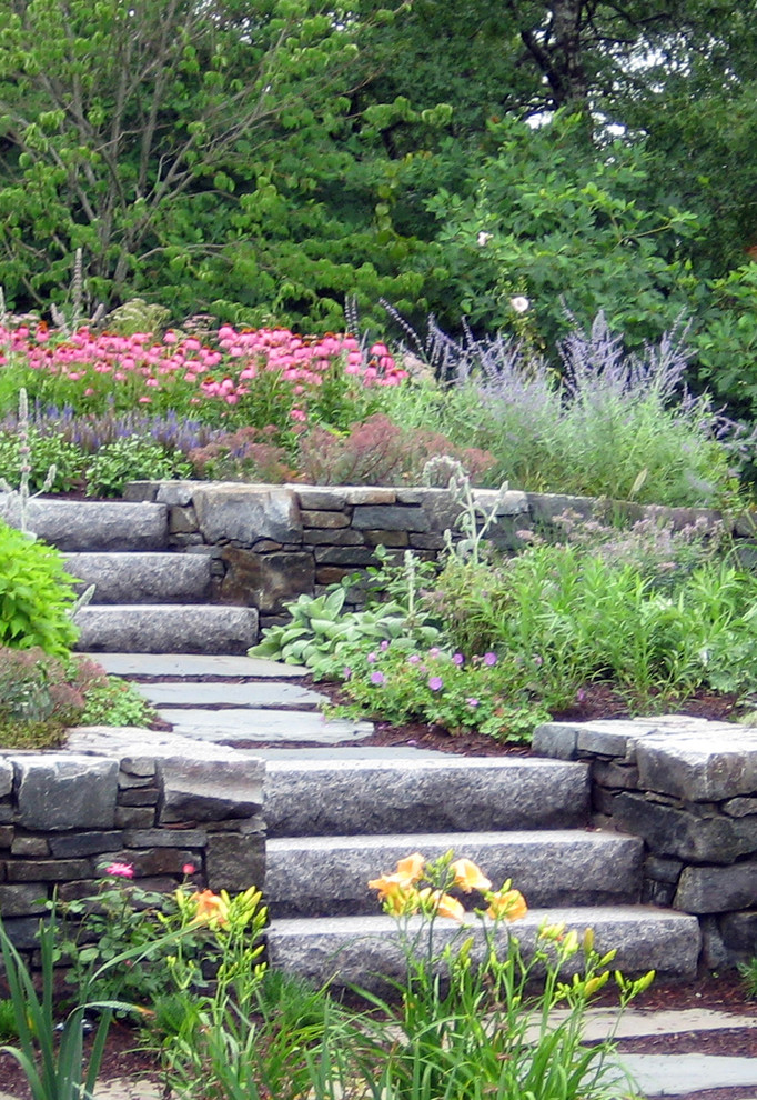 На фото: участок и сад в стиле неоклассика (современная классика) с подпорной стенкой, полуденной тенью и покрытием из каменной брусчатки
