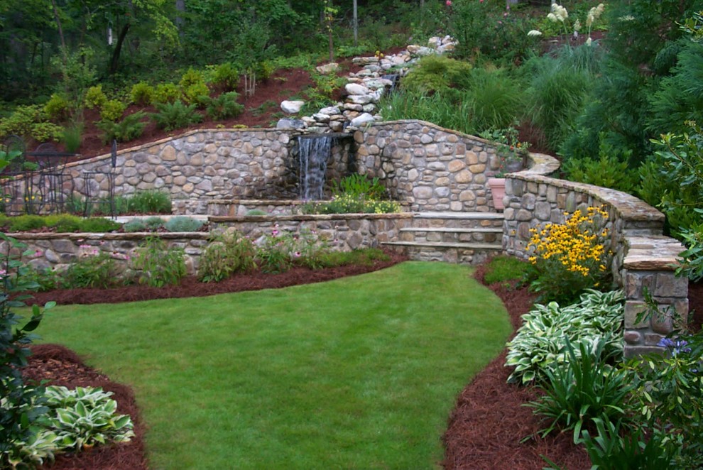 Diseño de jardín mediterráneo grande en patio trasero con fuente, exposición reducida al sol y adoquines de piedra natural