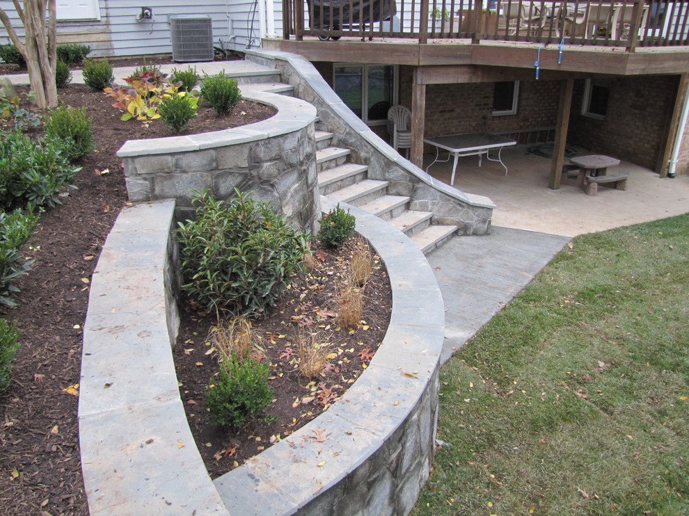 Photo of a medium sized traditional back partial sun garden in DC Metro with a retaining wall and natural stone paving.
