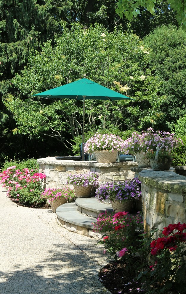 Ejemplo de jardín clásico grande en verano en patio trasero con jardín francés, muro de contención, exposición total al sol y adoquines de piedra natural