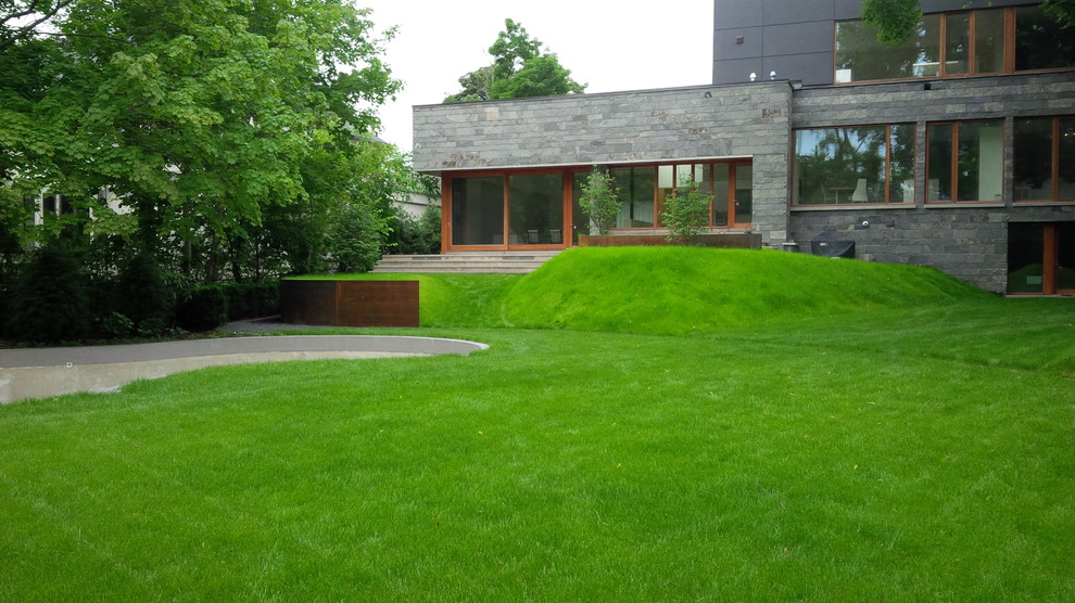 Foto di un grande giardino minimalista esposto a mezz'ombra dietro casa in primavera con un muro di contenimento e ghiaia