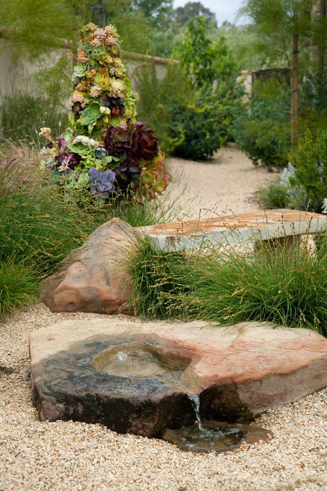 Imagen de jardín mediterráneo en patio lateral con fuente y gravilla