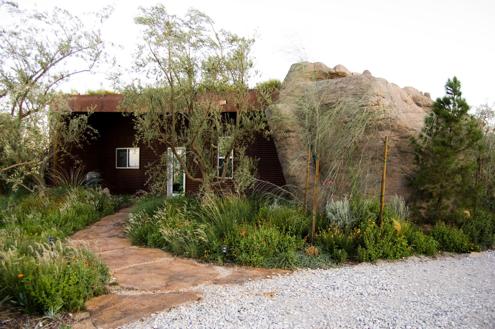 This is an example of a large modern front xeriscape garden in Los Angeles with a garden path and natural stone paving.