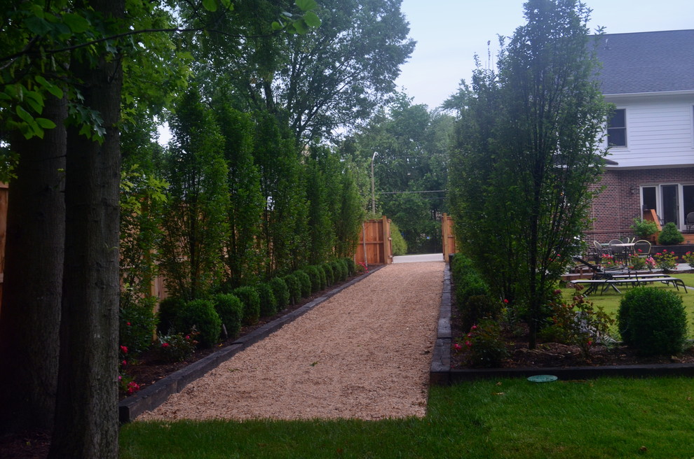 Diseño de jardín clásico grande en patio trasero con jardín francés y gravilla