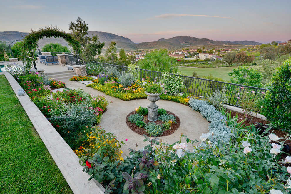 Foto di un ampio giardino formale mediterraneo esposto in pieno sole dietro casa in primavera con un ingresso o sentiero e pavimentazioni in cemento