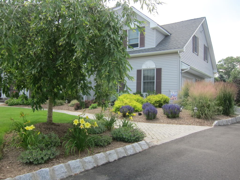 This is an example of a large traditional partial sun front yard brick landscaping in New York for summer.