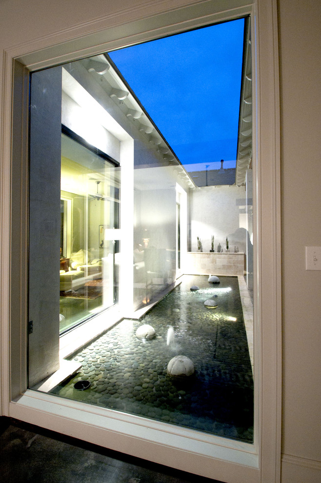 Photo of a mid-sized contemporary partial sun courtyard stone landscaping in New Orleans.