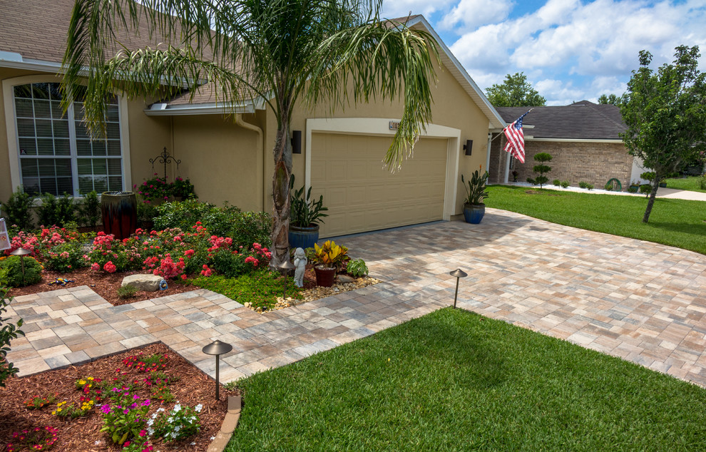 Expansive classic front driveway full sun garden for summer in Jacksonville with a retaining wall and natural stone paving.