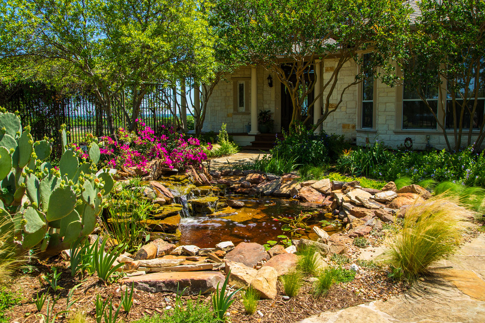 Inspiration for a large farmhouse front xeriscape full sun garden in Dallas with a pond and natural stone paving.