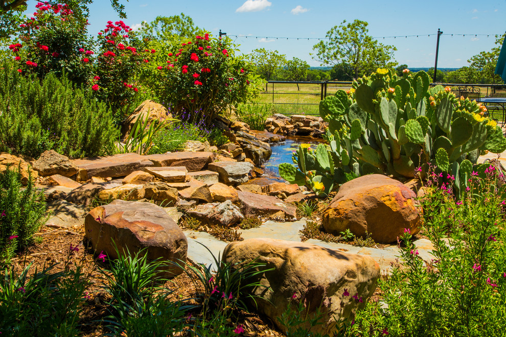 Modelo de jardín de secano de estilo de casa de campo grande en patio trasero con estanque, exposición total al sol y adoquines de piedra natural