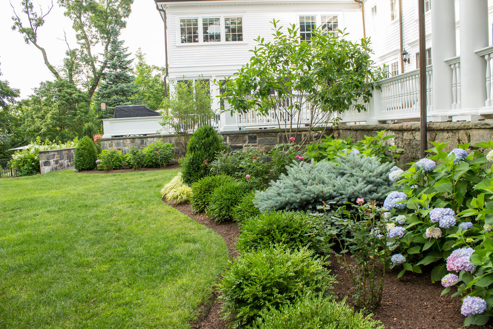 Diseño de jardín clásico extra grande en verano en patio trasero con exposición total al sol y mantillo