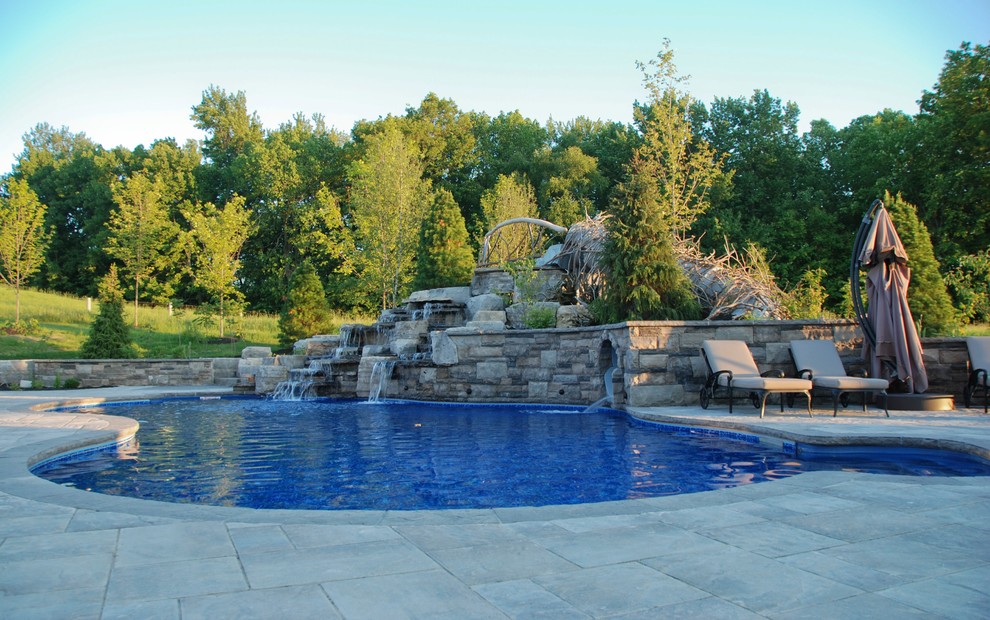 Large traditional back swimming pool in Toronto with a water feature and concrete paving.