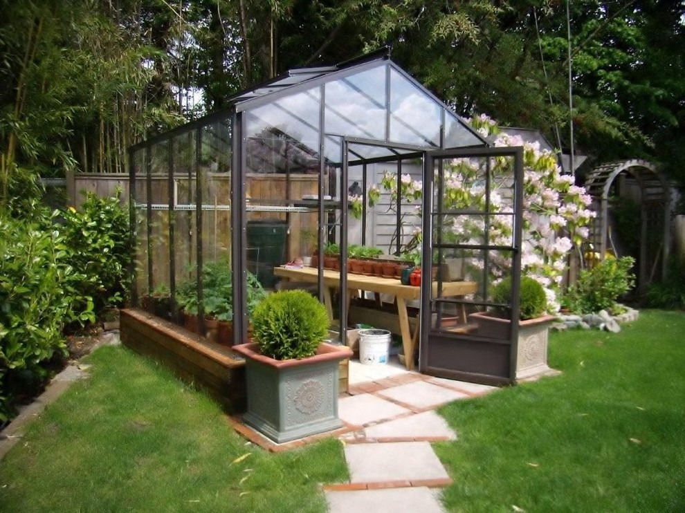 На фото: маленький весенний регулярный сад на заднем дворе в современном стиле с растениями в контейнерах, полуденной тенью и покрытием из каменной брусчатки для на участке и в саду