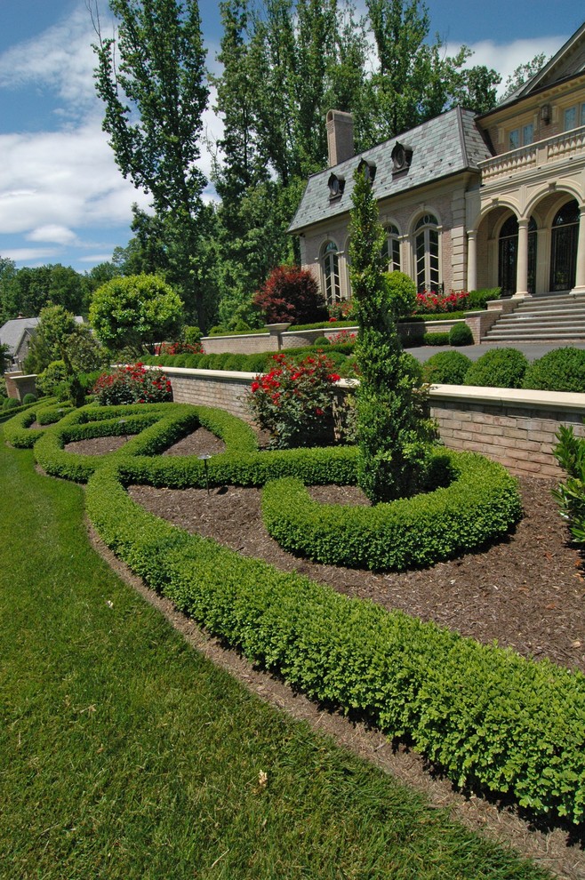 На фото: солнечный регулярный сад на переднем дворе в классическом стиле с хорошей освещенностью