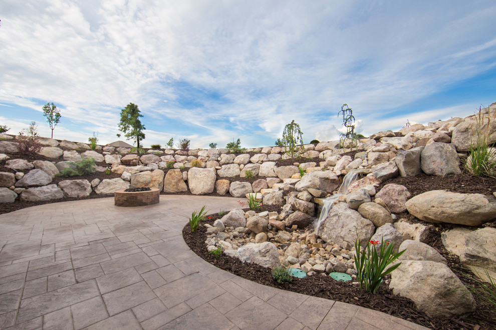 This is an example of an expansive traditional back partial sun garden for summer in Salt Lake City with a water feature and concrete paving.