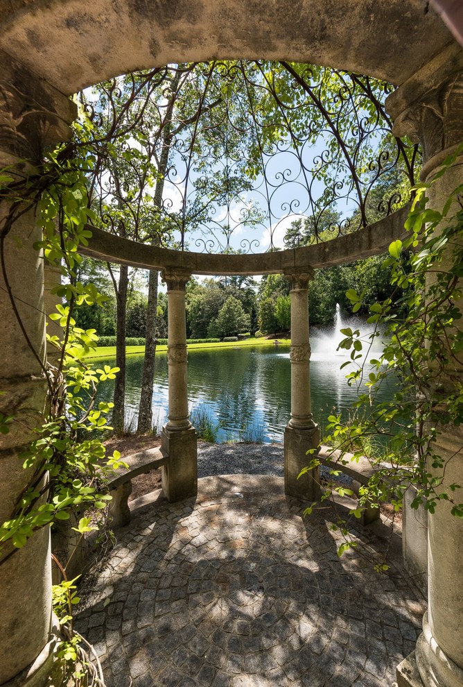 Réalisation d'un jardin à la française arrière tradition avec un bassin et des pavés en pierre naturelle.