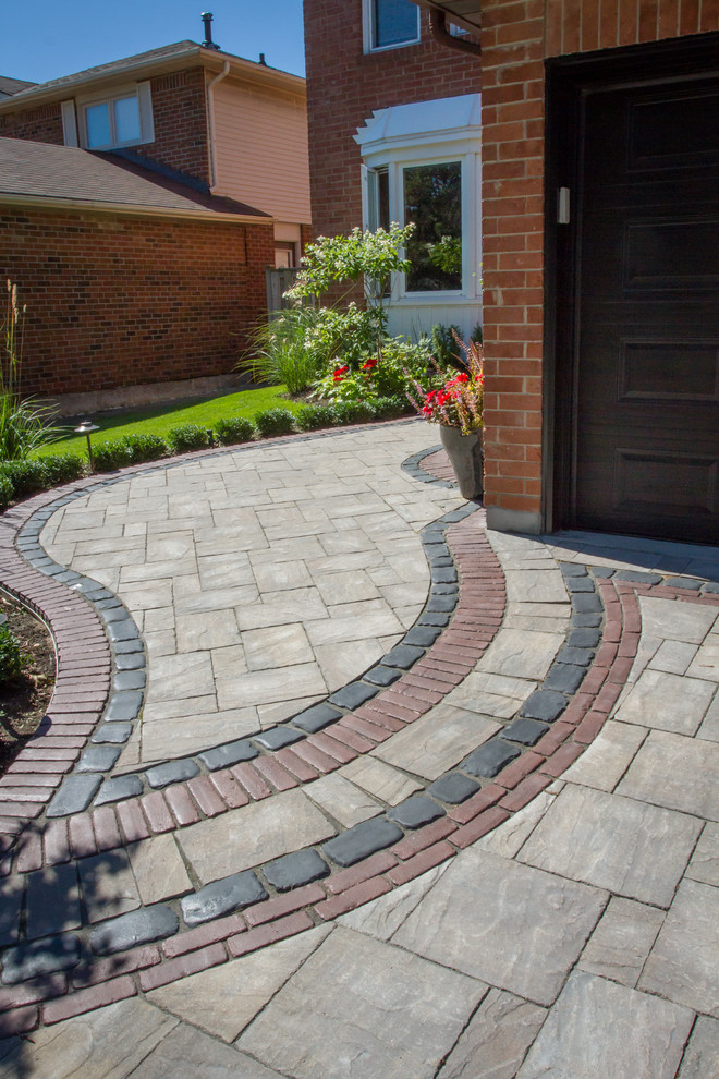 Inspiration for a medium sized traditional front driveway partial sun garden for spring in Toronto with a potted garden and natural stone paving.