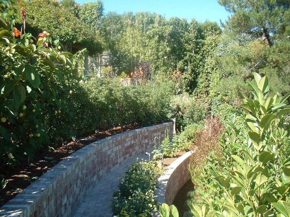 Idéer för en stor modern formell trädgård i full sol i slänt, med en stödmur och marksten i tegel