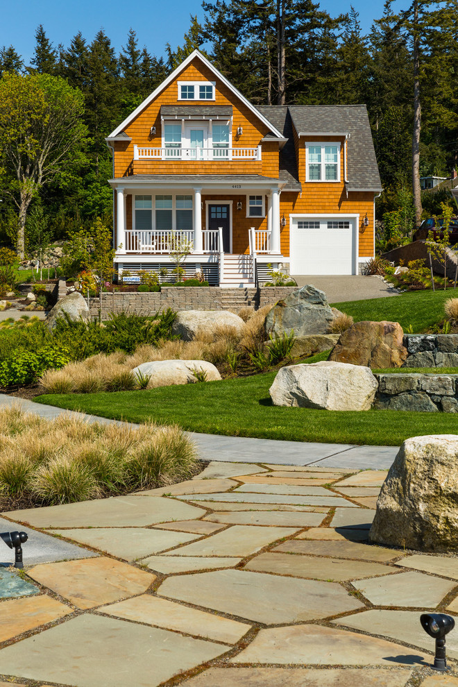 Immagine di un grande giardino davanti casa con un muro di contenimento e pavimentazioni in pietra naturale