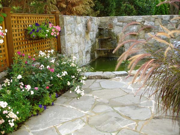 Immagine di un giardino moderno di medie dimensioni e dietro casa con fontane e pavimentazioni in pietra naturale