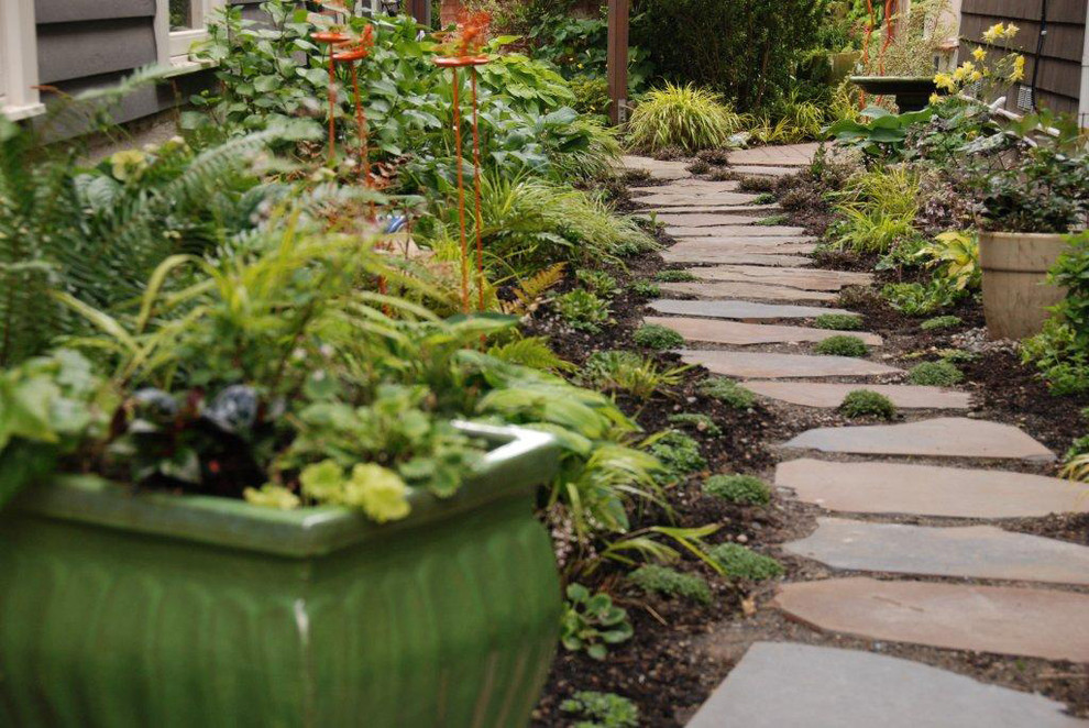 Idéer för att renovera en eklektisk trädgård längs med huset, med naturstensplattor