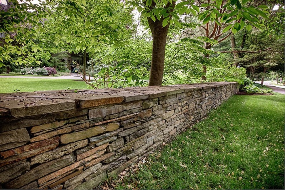 Foto di un grande giardino tradizionale dietro casa con un muro di contenimento e pavimentazioni in pietra naturale
