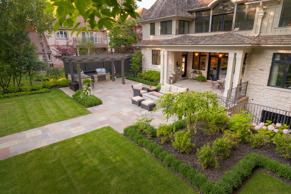 На фото: большой регулярный сад на заднем дворе в классическом стиле с подпорной стенкой и покрытием из каменной брусчатки с
