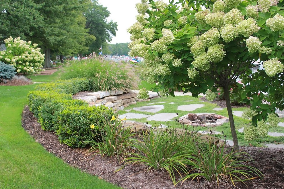 Esempio di un grande giardino formale american style esposto a mezz'ombra dietro casa in primavera con un muro di contenimento e pavimentazioni in pietra naturale