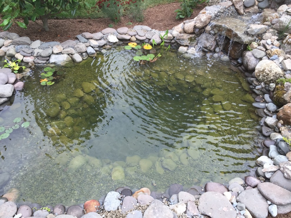 Photo of a mid-sized traditional partial sun backyard water fountain landscape in New York.