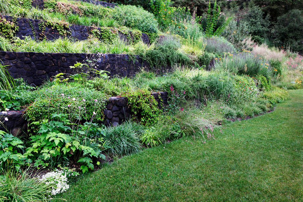 Idéer för mellanstora rustika trädgårdar i skuggan på våren, med en stödmur och naturstensplattor