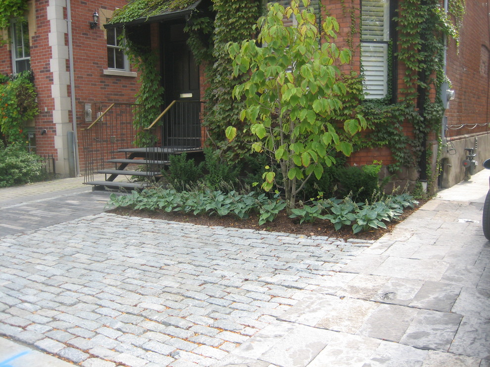 Medium sized traditional front driveway partial sun garden for summer in Toronto with a garden path and natural stone paving.