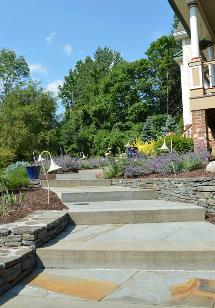 Immagine di un giardino chic davanti casa con un muro di contenimento e pavimentazioni in pietra naturale