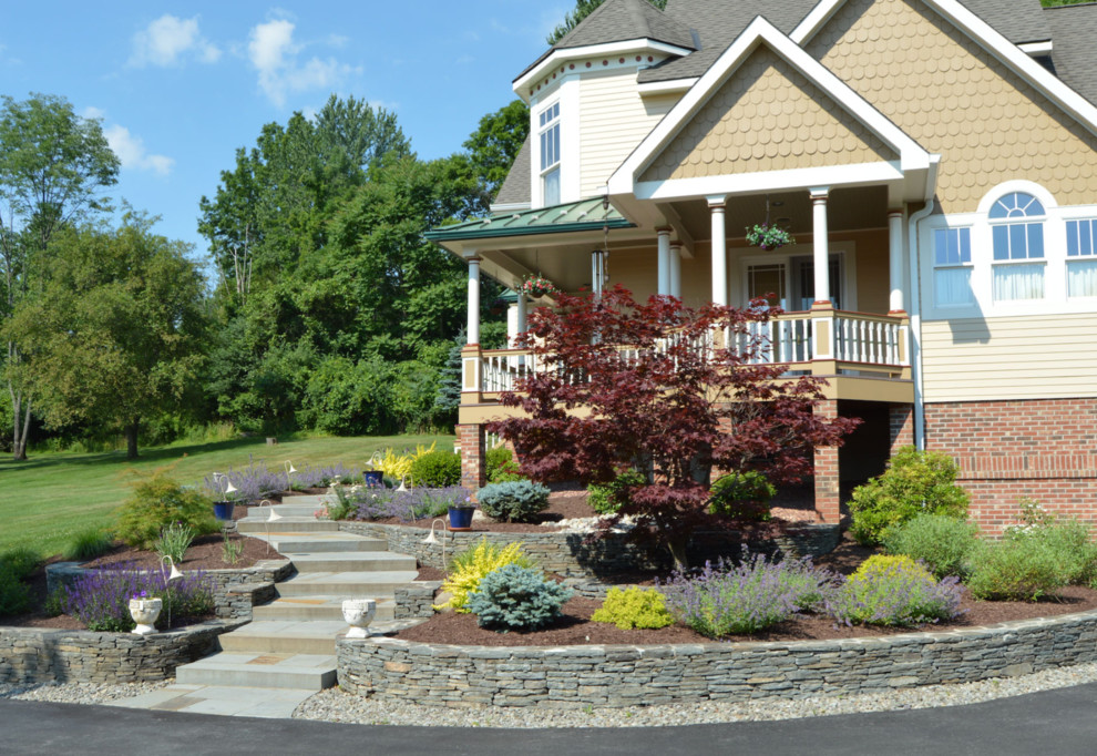 Photo of a traditional front garden in New York with a retaining wall and natural stone paving.
