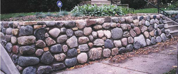 Modelo de jardín clásico de tamaño medio en patio delantero con muro de contención y adoquines de piedra natural