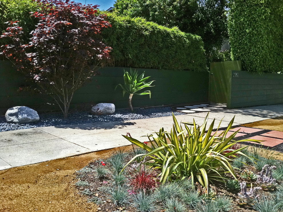Bild på en mellanstor funkis formell trädgård i full sol framför huset, med en trädgårdsgång och marksten i betong