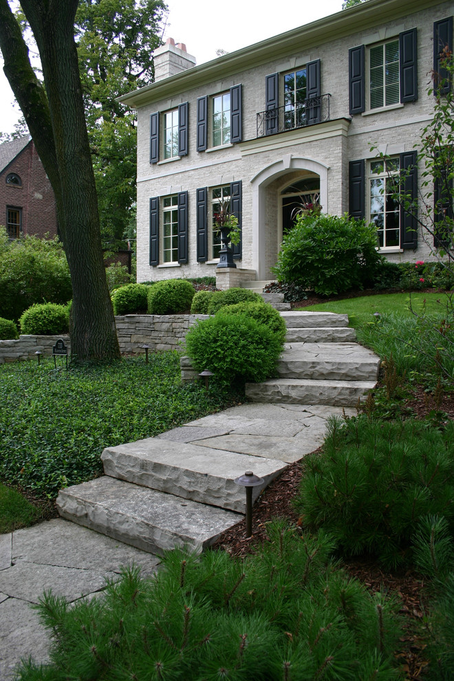 Photo of a large traditional partial sun front yard stone retaining wall landscape in Chicago for summer.