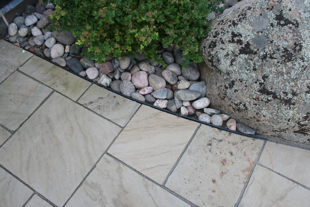 This is an example of a small traditional front driveway partial sun garden in Denver with natural stone paving.