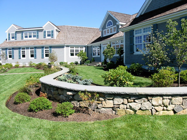 This is an example of a large traditional back driveway full sun garden in Boston with natural stone paving.