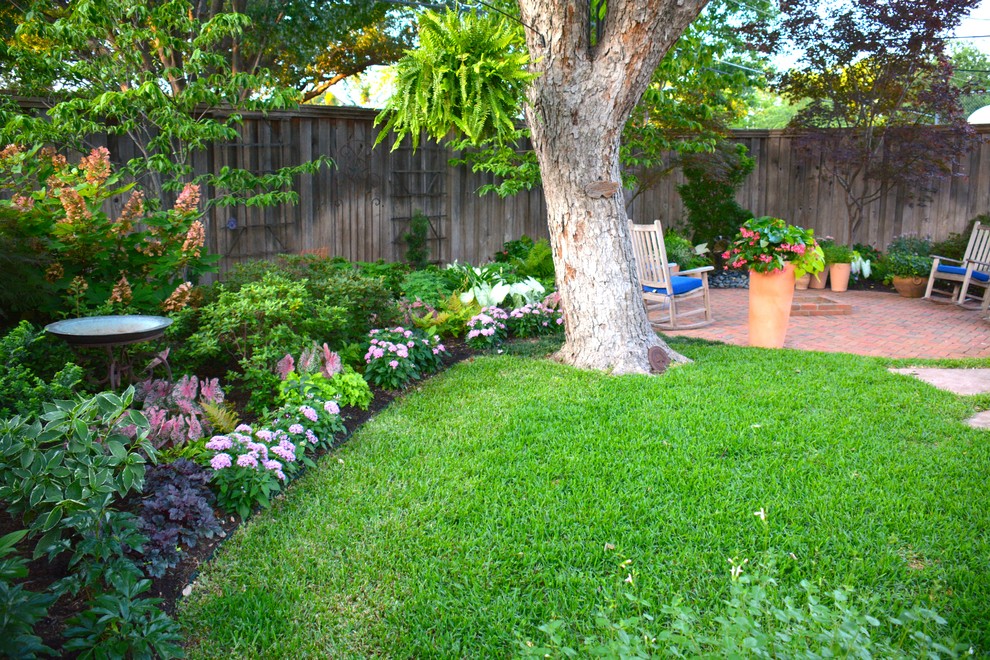 Cette image montre un jardin arrière traditionnel de taille moyenne et l'été avec une exposition ombragée et un paillis.