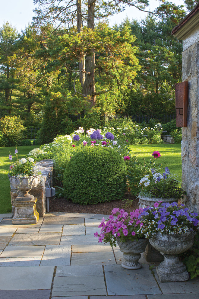 Modelo de camino de jardín de estilo americano grande en primavera en patio delantero con exposición parcial al sol, adoquines de piedra natural y jardín francés