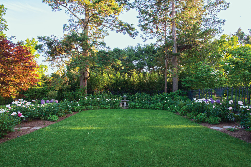 Bild på en stor amerikansk trädgård i delvis sol på våren, med en trädgårdsgång och naturstensplattor