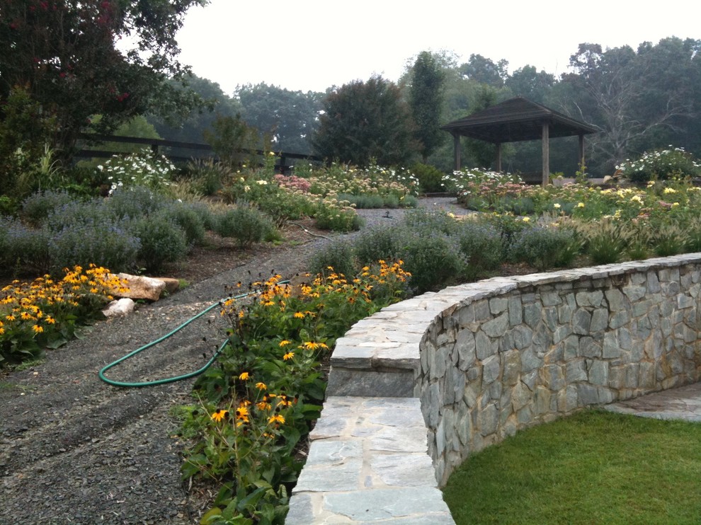 На фото: большой летний регулярный сад на заднем дворе в стиле рустика с садовой дорожкой или калиткой, полуденной тенью и покрытием из каменной брусчатки