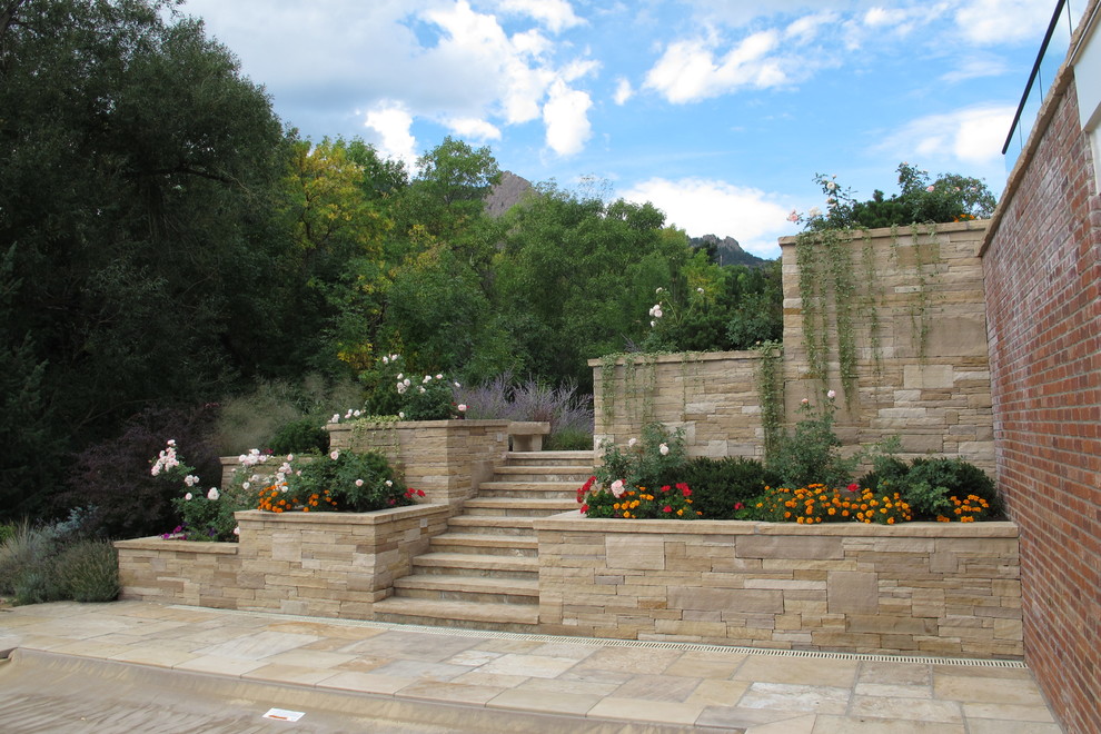 Foto di un giardino contemporaneo esposto in pieno sole dietro casa e di medie dimensioni in estate con pavimentazioni in pietra naturale e un muro di contenimento