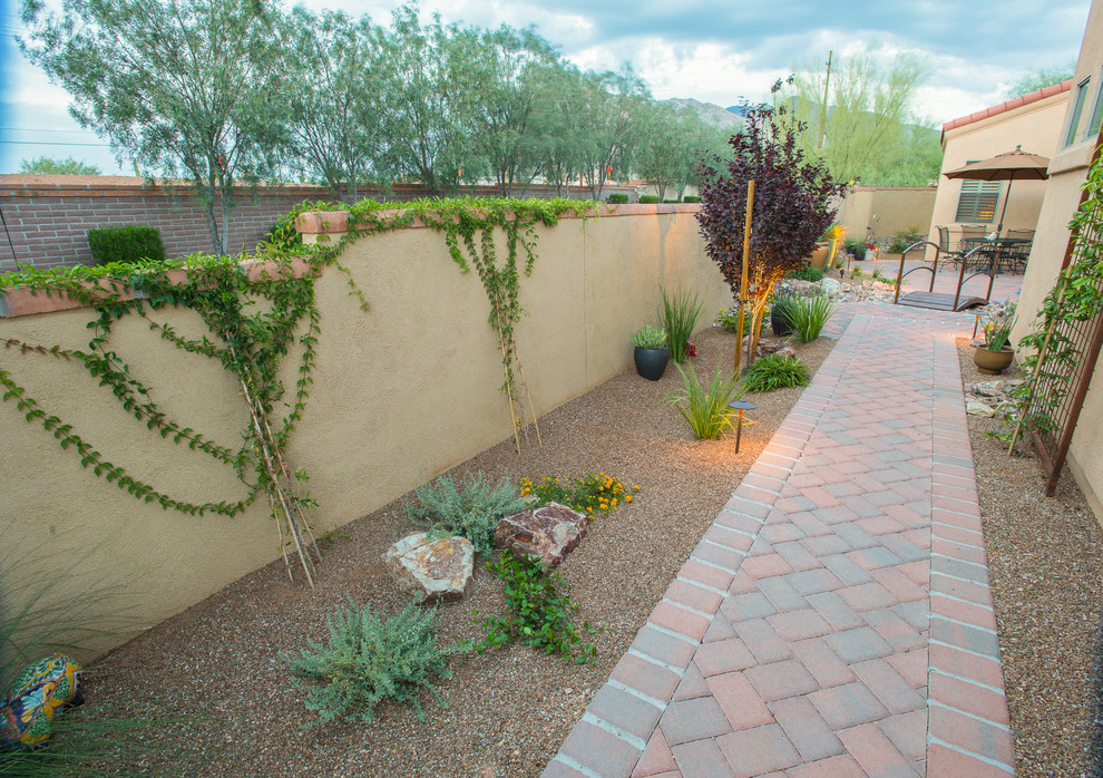 Esempio di un giardino xeriscape stile americano esposto a mezz'ombra nel cortile laterale e di medie dimensioni con un ingresso o sentiero e pavimentazioni in mattoni