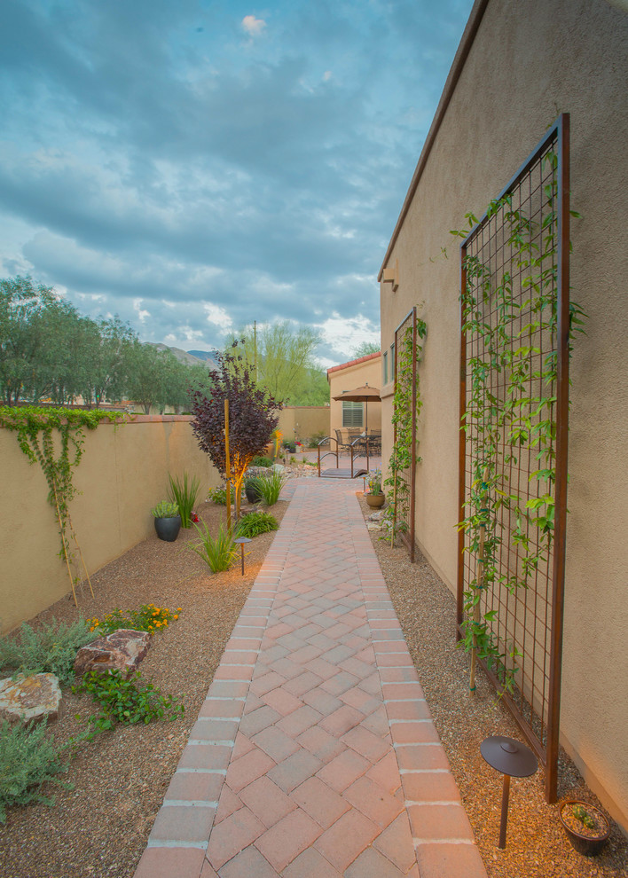 This is an example of a mid-sized southwestern drought-tolerant, partial sun and desert side yard brick landscaping in Phoenix.