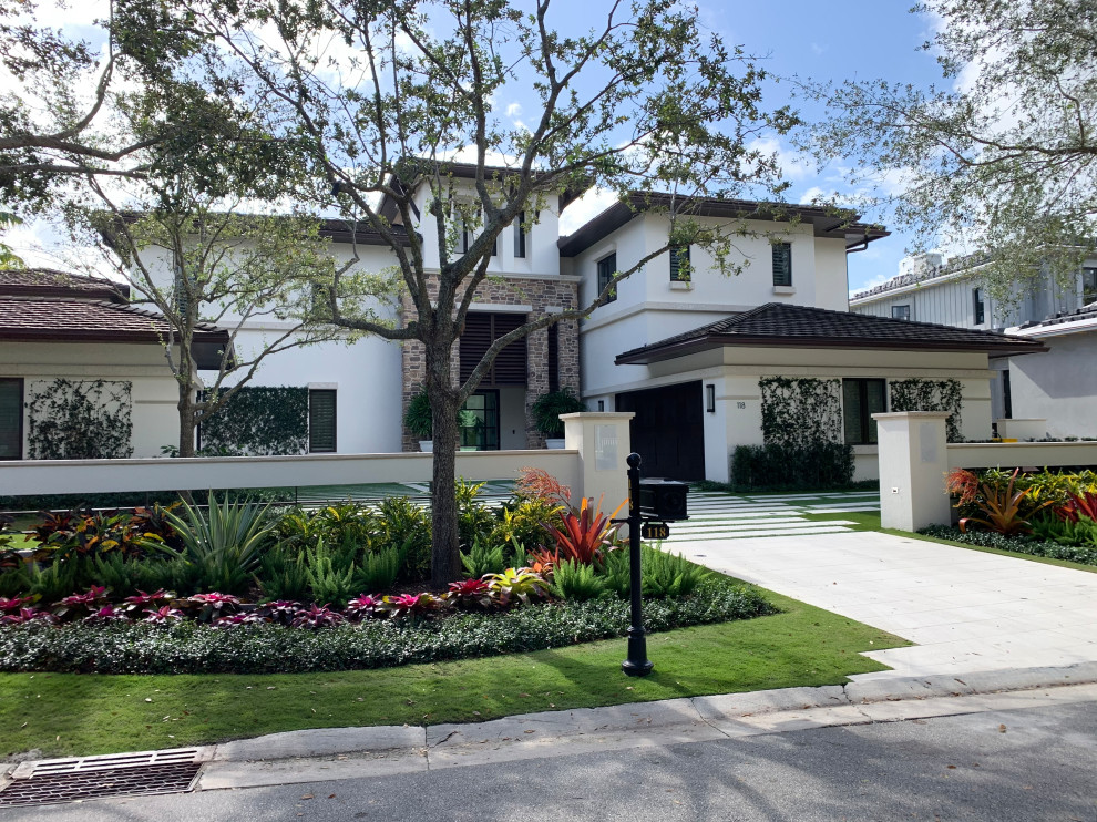 This is an example of a medium sized classic front driveway partial sun garden in Miami with natural stone paving.